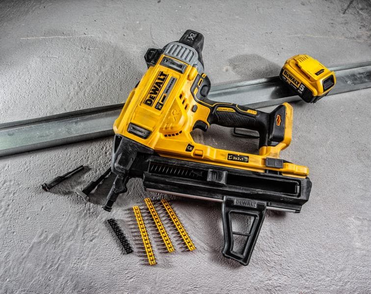 DEWALT DCN890P2 battery nailer with accessories and fasteners on a concrete surface.